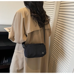 Detail of the black nylon crossbody bag showing the adjustable strap and back view on a model