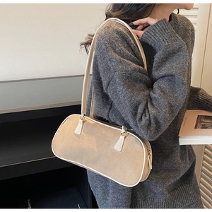 Detail view of beige faux suede underarm bag on shoulder showing soft velvet texture