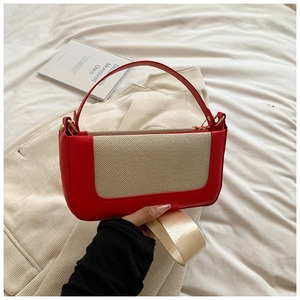 Dettaglio borsa in pelle rossa con inserto in tela beige e ampia tracolla in tessuto