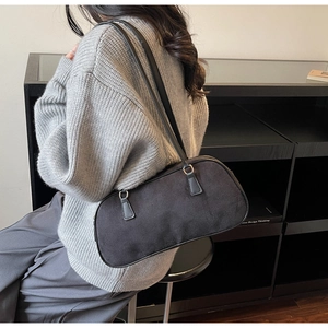 Close-up of a minimalist black suede baguette shoulder bag with silver hardware detail
