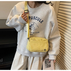 Detail of bright yellow nylon crossbody bag featuring multi-zip pockets and wide strap
