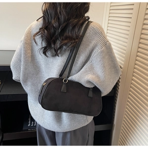 Side view of model wearing a vintage black suede baguette bag with slim double handles