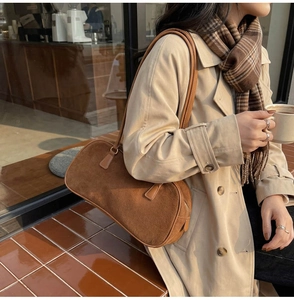 Brown faux suede baguette bag worn by a model in a cozy autumn café setting