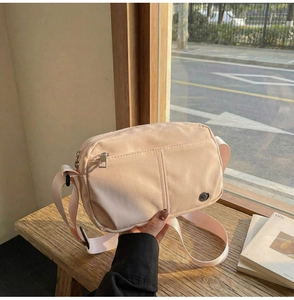 Detail of soft pink crossbody square bag featuring durable fabric and adjustable strap