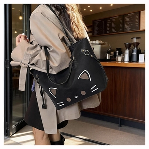 Detail shot of a black matte leather tote bag with a minimalist cat face on a model