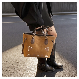 Detail shot of a brown tote bag featuring minimalist cat embroidery and metal ring hardware
