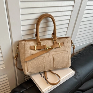 Retro denim-textured handbag with brown leather trim and dual pockets shown on a white stand