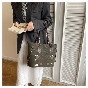 Detail of dark green matte tote bag featuring a minimalist cat face and brown handles