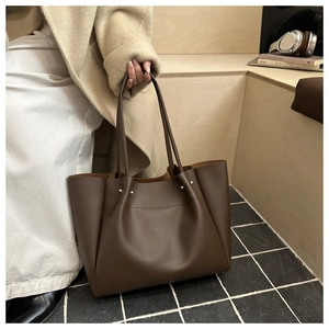 Detail of dark brown leather tote bag with sturdy straps and metal rivet accents