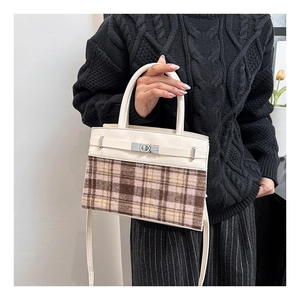 Dettaglio dell'elegante borsa bicolore con chiusura a scatto in metallo e pannello in tweed