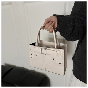 Detail of white PU leather tote with metal rivets and decorative strap closure