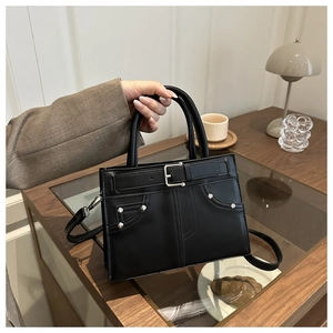 Detail of black leather tote bag with silver studs and adjustable shoulder strap