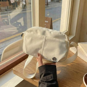 Minimalist beige crossbody bag with dual pockets and adjustable strap for daily use