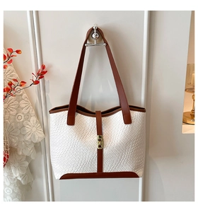 Detail view of woven texture tote bag with contrasting brown trim and golden lock