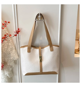 Close-up of woven texture tote bag with brown leather handles and golden metal lock