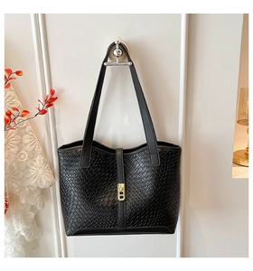 Detail of black woven texture tote bag with elegant golden metal buckle and shoulder straps