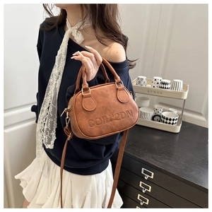 Detailed view of brown PU leather shell bag with embossed logo and adjustable strap