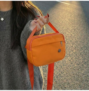 Vue détaillée du sac fourre-tout orange en nylon avec sangle réglable et logo en métal