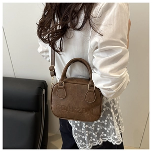 Brown vintage shell crossbody bag with embossed logo worn by a model in lifestyle shot
