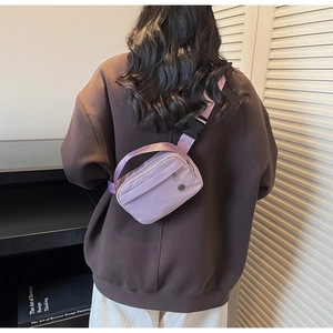 Détail d'un sac bandoulière en nylon violet clair avec compartiments zippés sur modèle