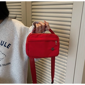 Détail du sac bandoulière en nylon rouge avec poche zippée et bandoulière réglable