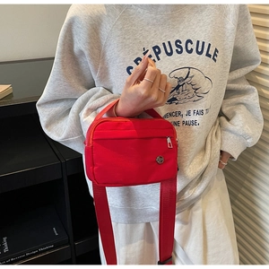 Détail du sac bandoulière rouge en nylon avec logo métal et bandoulière large