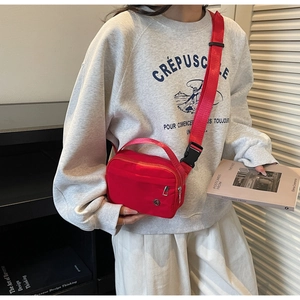 Détail du sac bandoulière en nylon rouge avec sangle réglable porté par un mannequin