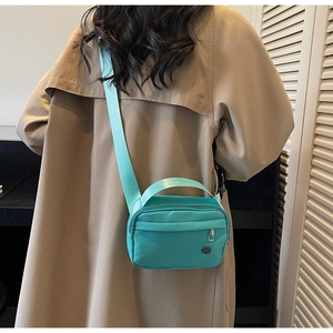 Vue arrière d'un mannequin portant le sac bandoulière en nylon vert menthe à large sangle