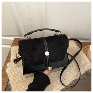 Détail du sac à main en daim noir avec fermoir doré sur fond en maille beige