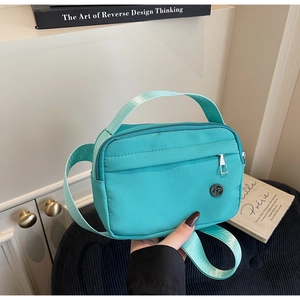 Gros plan d'un sac bandoulière en nylon vert menthe sur un tabouret en velours