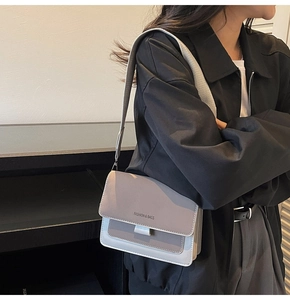 Detail of color-block crossbody bag with wide strap and fashion text on the flap