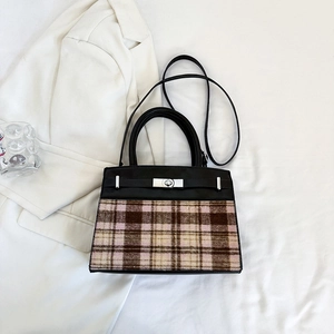 Detail of trendy checkered fabric handbag with metallic twist lock and black leather trim
