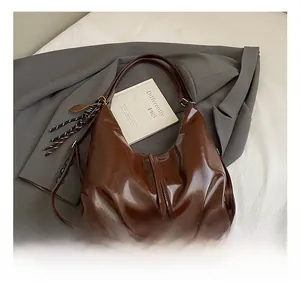 Detail view of dark brown glossy leather tote bag with striped tassel and racquet charm
