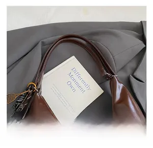 Detail of dark brown oil wax leather tote bag with vintage gloss and tennis racket charm