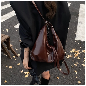 Close-up of deep brown glossy leather hobo bag with natural vintage texture and strap