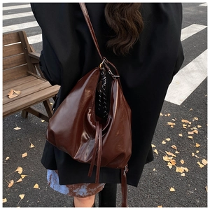 Deep brown glossy leather tote bag shown in a street scene with autumn ginkgo leaves