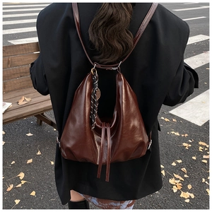Detailed street style view of dark brown pleated tote bag with silk scarf and charms