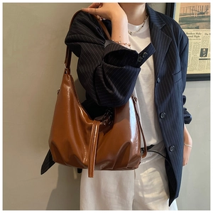 Detail of deep brown glossy hobo bag with adjustable strap on professional model
