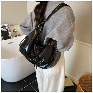 Detail of glossy black oversized tote bag with natural pleats and metallic buckle
