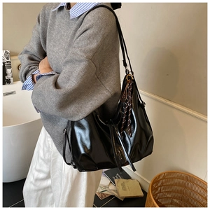 Macro shot of large black glossy leather tote bag with drawstring tassels and hobo style