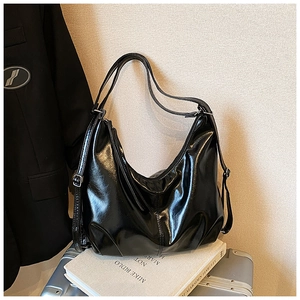 Detail of glossy black patent leather Hobo bag with adjustable straps and metallic buckles