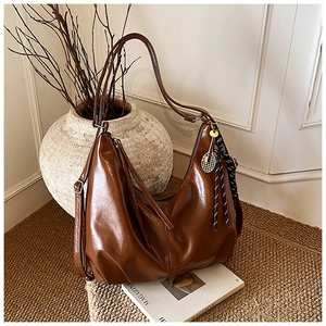 Detail of dark brown leather hobo bag with vintage texture and tennis racket charm