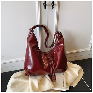 Close-up of burgundy hobo bag in glossy leather with stylish long tassel detail