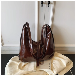 Close-up of deep brown oil wax leather tote bag with glossy finish and wide straps
