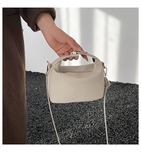 Detail of minimalist beige PU leather crossbody bag with gold hardware and top handle