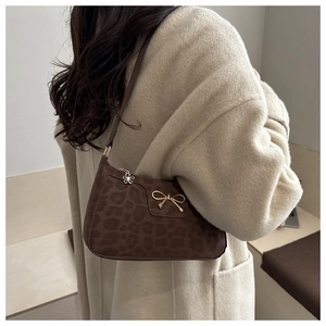 Detail of leopard print suede shoulder bag with gold bow and flower zipper pull