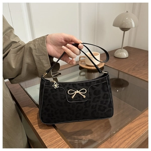 Detail of black leopard embossed handbag with gold bow and floral zipper charm