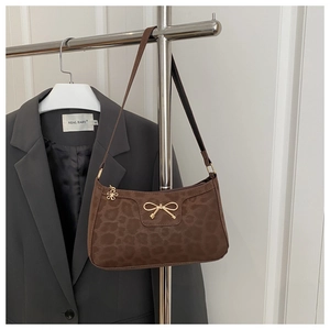 Detail of leopard print velvet underarm bag featuring a golden metal bow and floral zipper