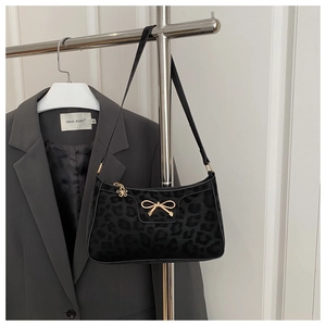 Macro view of leopard print baguette bag with gold bow clasp and floral zipper charm