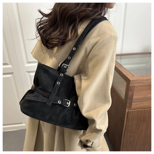 Detail of black suede shoulder bag featuring silver grommets and vintage buckle accents